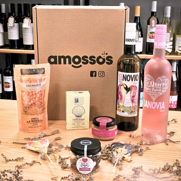 Pack regalo San Valentín de Amossos con vino El Novio Perfecto, vino La Novia Ideal, zamburiñas, cacahuetes con curry, paté de secreto ibérico con cerezas y dos piruetas de chocolate en forma de corazón sobre mesa.
