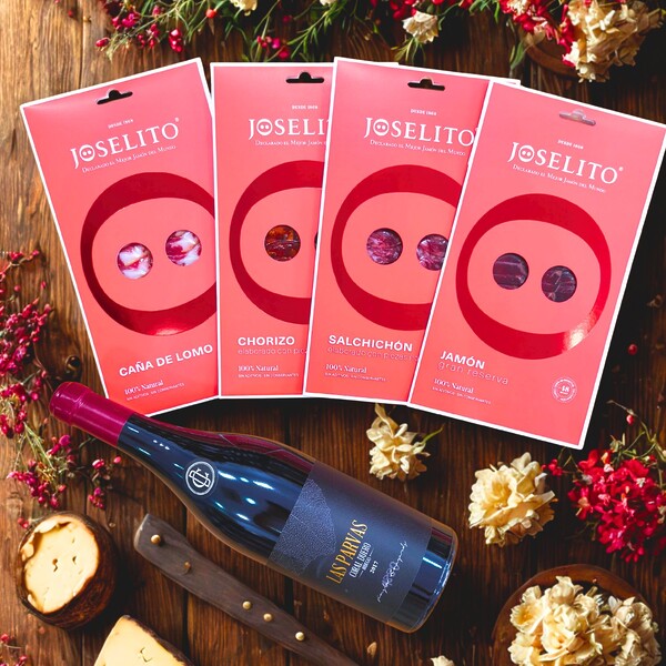 Bodegón con cuatro blísters de Joselito: jamón, lomo,salchichón y chorizo acompañados de una botella de vino crianza Las Parvas
